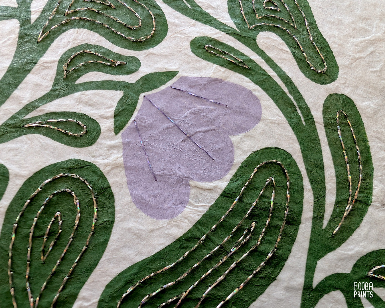 Close up on a handmade linocut and hand embroidered original linocut print. Details of hand embroidery with champagne and purple thread.