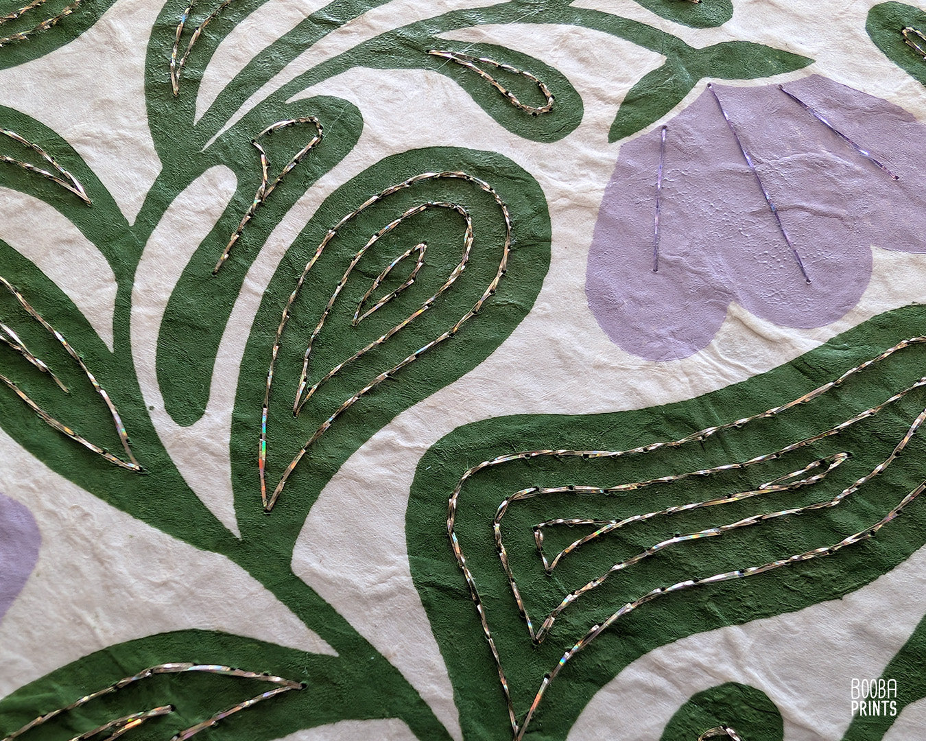 Close up on a handmade linocut and hand embroidered original linocut print. Details of hand embroidery with champagne and purple thread.