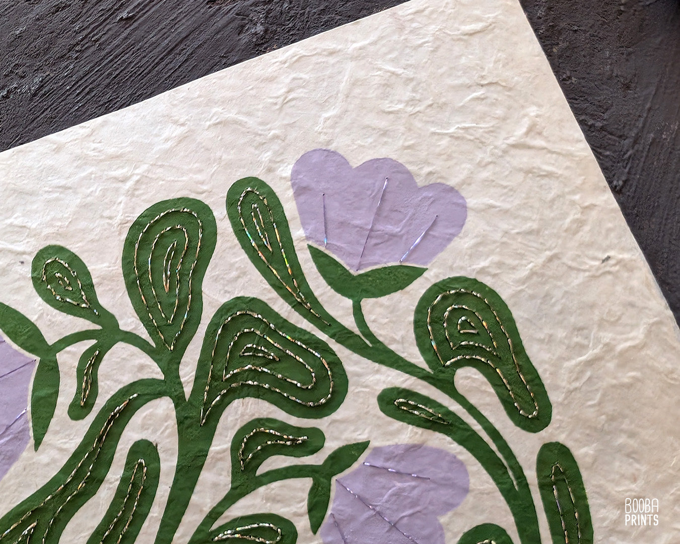 Close up on a handmade linocut and hand embroidered original linocut print. Details of hand embroidery with champagne and purple thread.