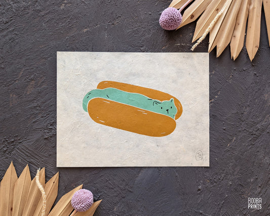 Original 2 color linocut print, printed in Ochre and mint green, showing a cute cat in a hot dog but. Cute whimsical art for your kitchen. Art by Booba Prints