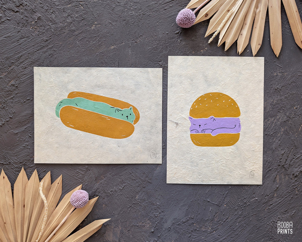 Original 2 color linocut print, printed in Ochre and mint green, showing a cute cat in a hot dog but. Cute whimsical art for your kitchen. Art by Booba Prints
