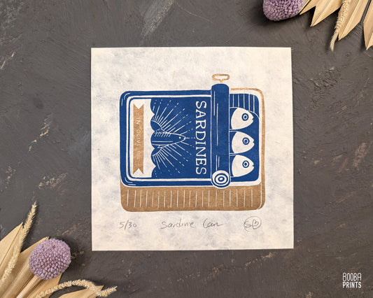 Original handmade linocut prints of Sardine Tin Can. Printed in blue and gold, using oil based ink on natural Lokta paper. Cute print for kitchen, stylized sardine print. Art by Booba Prints.