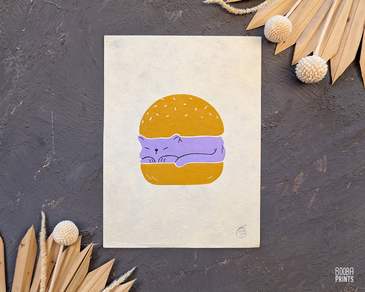 Original handmade linocut print of "Burger Cat" featuring a cute cat between 2 burger buns. Printed in 2 colors: lavender and yellow ochre. Original linocut print in he size of 6"x8". Art by Booba Prints