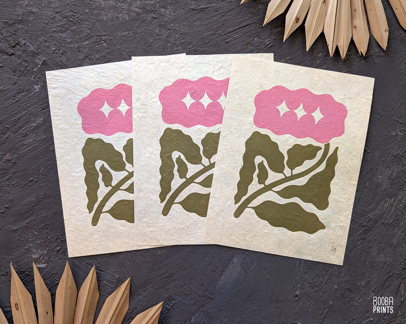 Minimalist mini linocut print of a hand carved flower, printed in soft green and pink ink on white paper, handmade botanical wall art. Cozy house warming gift. Art by Booba Prints