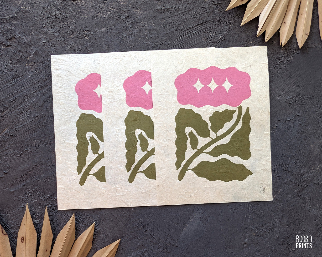 Minimalist mini linocut print of a hand carved flower, printed in soft green and pink ink on white paper, handmade botanical wall art. Cozy house warming gift. Art by Booba Prints