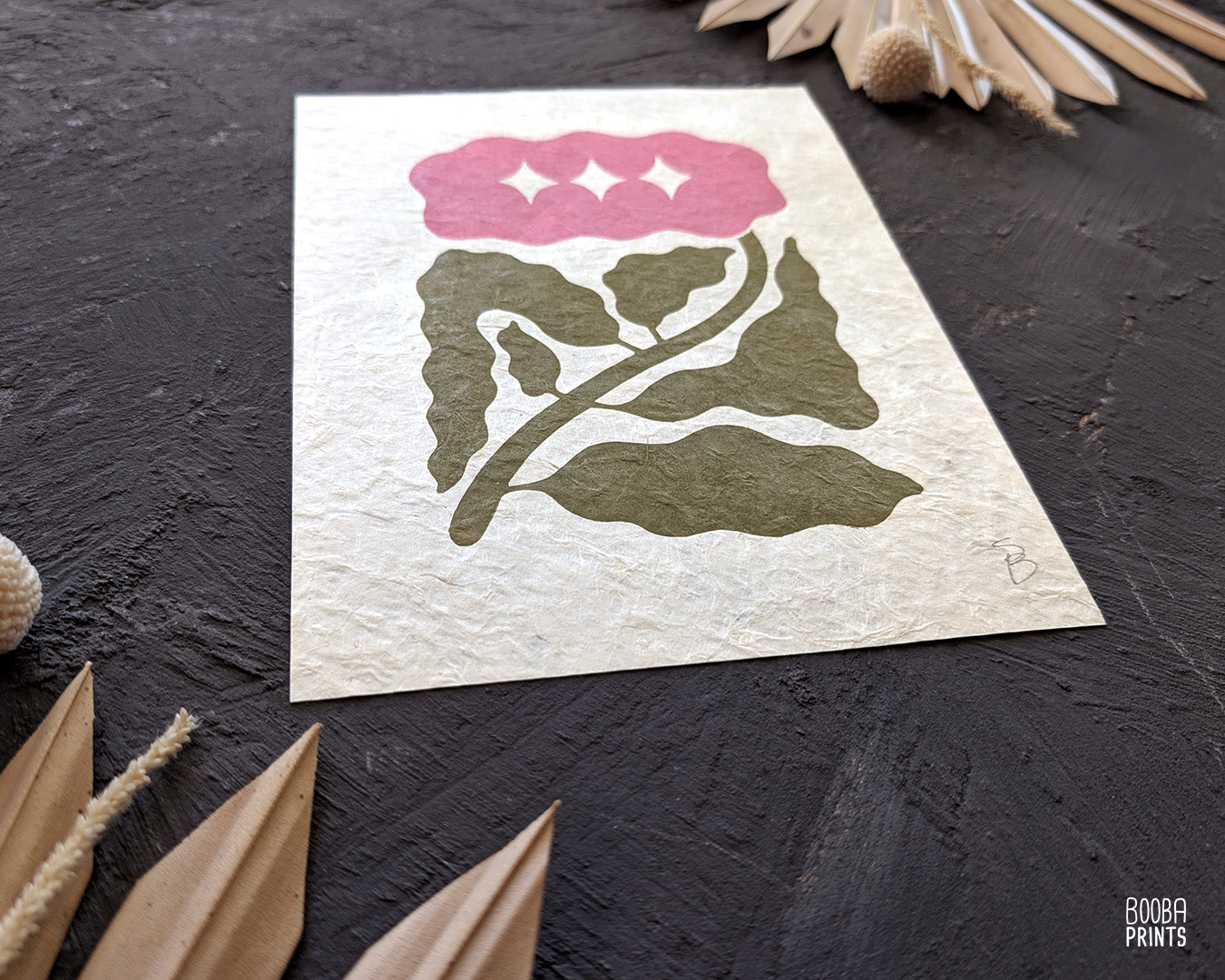 Minimalist mini linocut print of a hand carved flower, printed in soft green and pink ink on white paper, handmade botanical wall art. Cozy house warming gift. Art by Booba Prints