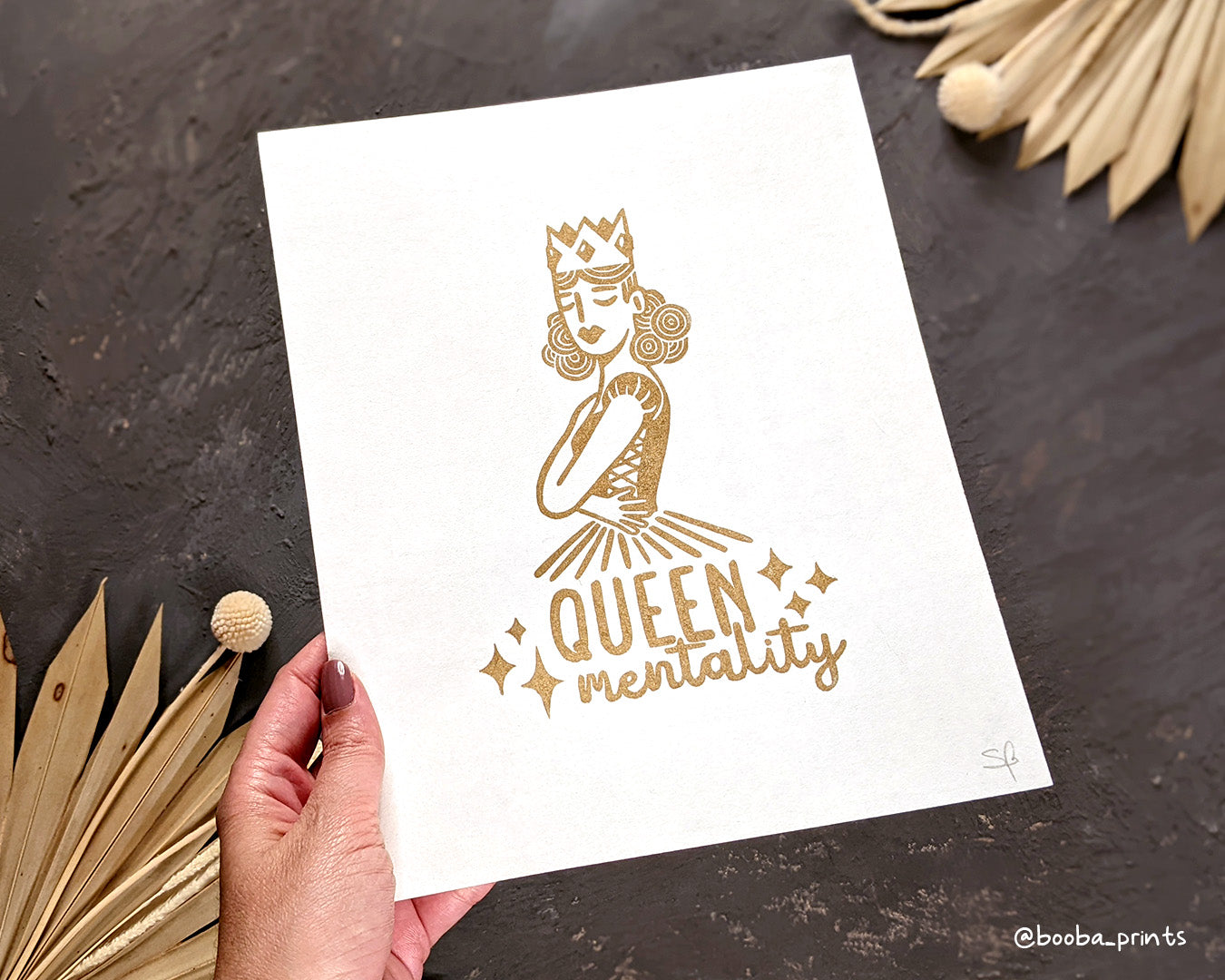 Handmade linocut print of Queen Mentality. Stylized illustration of a queen hugging herself and the text queen mentality. Printed with black or gold oil based ink on natural or Hosho paper. Empowering print for home decor. Super Seconds Festival, sale of samples and seconds. Artwork by Booba Prints.