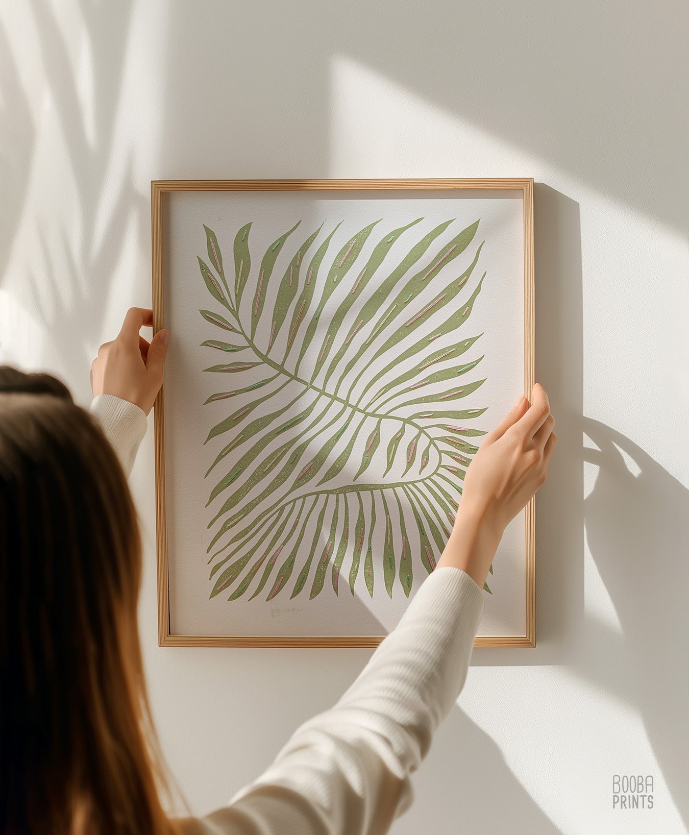 Person holding a framed print of a green leaf against a white wall. Original hand made, and printed and hand embroidered linocut print. special mixed media piece for plant lover
