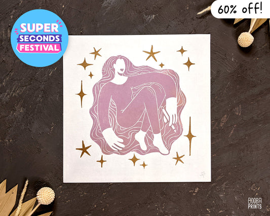 Super Seconds Festival. handmade linocut print on Inspiration Girl. Stylized print of woman holding pencil surrounded by metallic gold stars. Pink and gold print. Art by Booba Prints. Super Seconds Festival sale. Print is 60% off.
