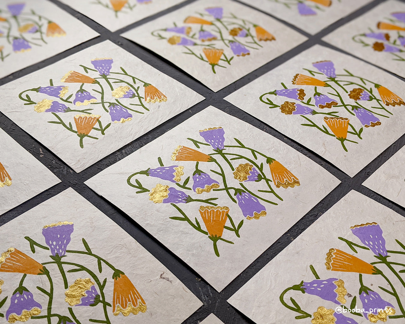 Handmade linocut print in the theme of Flora and Fauna. Floral print in 4 colors orange, purple green and gold. Printed with oil based ink and finished with metallic paint. Art by Booba Prints.